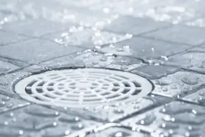 Floor drain, running water in shower, tinted black and white image