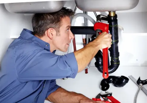 Plumber fixing pipe under sink