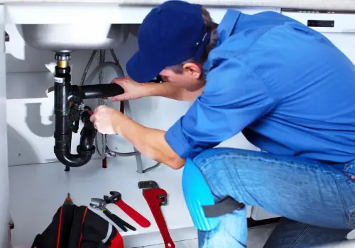 Plumber repairing pipes under sink